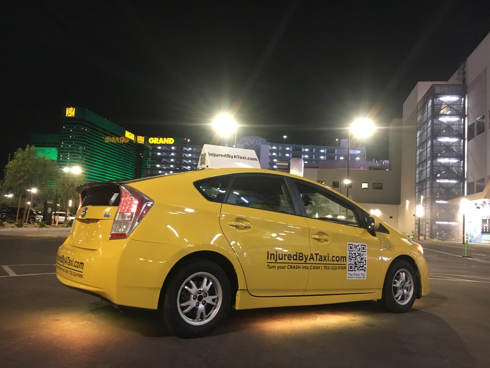 The yellow InjuredByATaxi.com taxi near MGM Grand at night